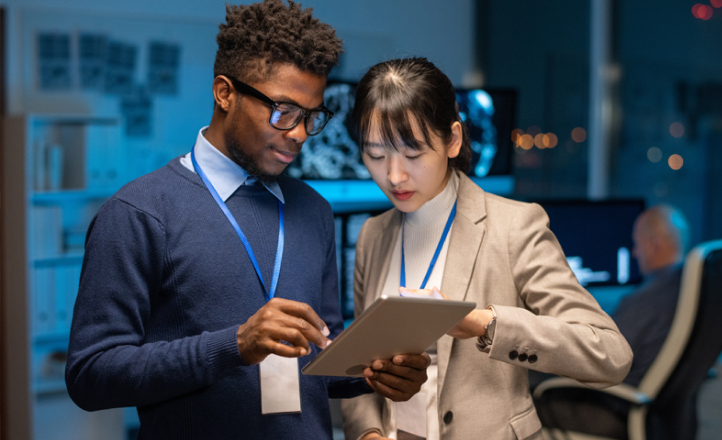 A young man and a young woman look at a tablet together.